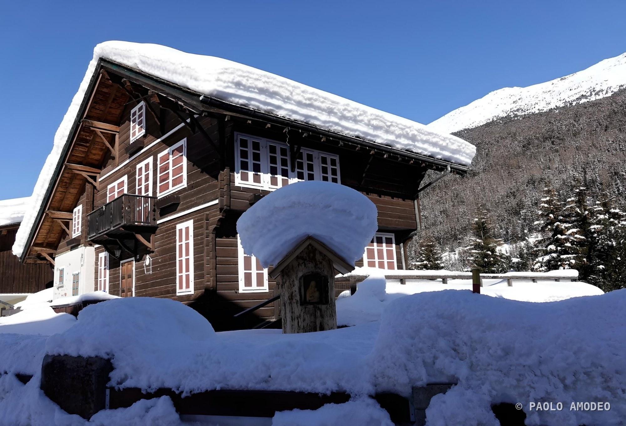 Baita innevata con le Alpi sullo sfondo